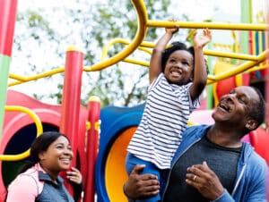 a man holding a child up on a playground equipment