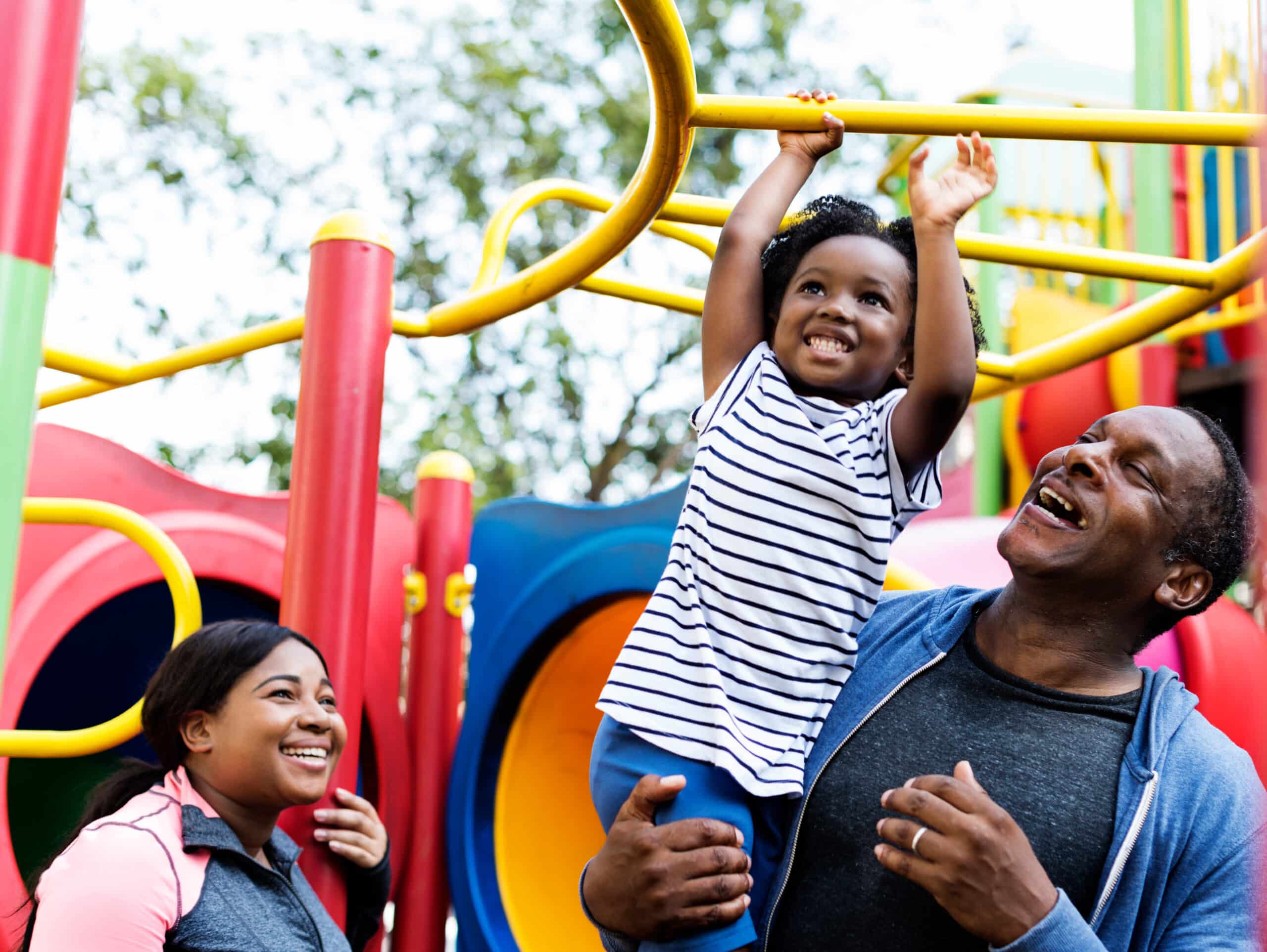 a man holding a child up on a playground equipment