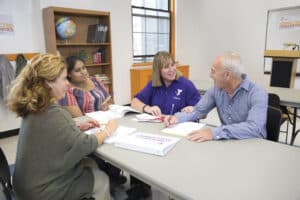a group of people sitting around a table | Bridging Healthcare and Community